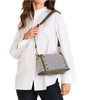 Woman wearing a white shirt with a green and beige handbag over her shoulder on a white background