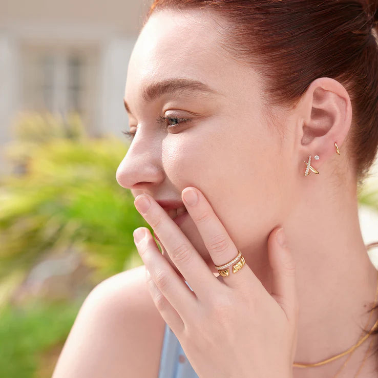 Woman wearing gold earrings and ring outdoors
