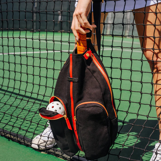 COURTSIDE SLING in Black/ Gold with Red Zip