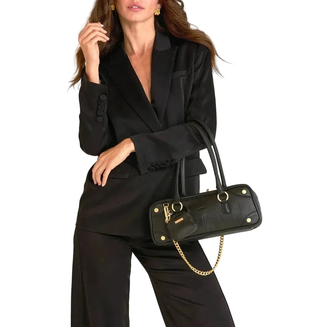 Woman in a black suit holding a matching black handbag on a white background