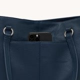 Navy blue leather handbag with a phone in the front pocket