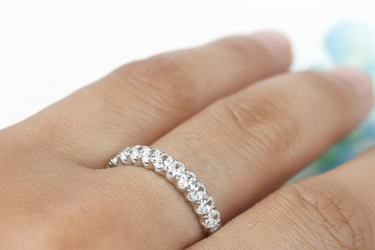 Silver ring with small diamonds on a person's finger against a blurred natural background