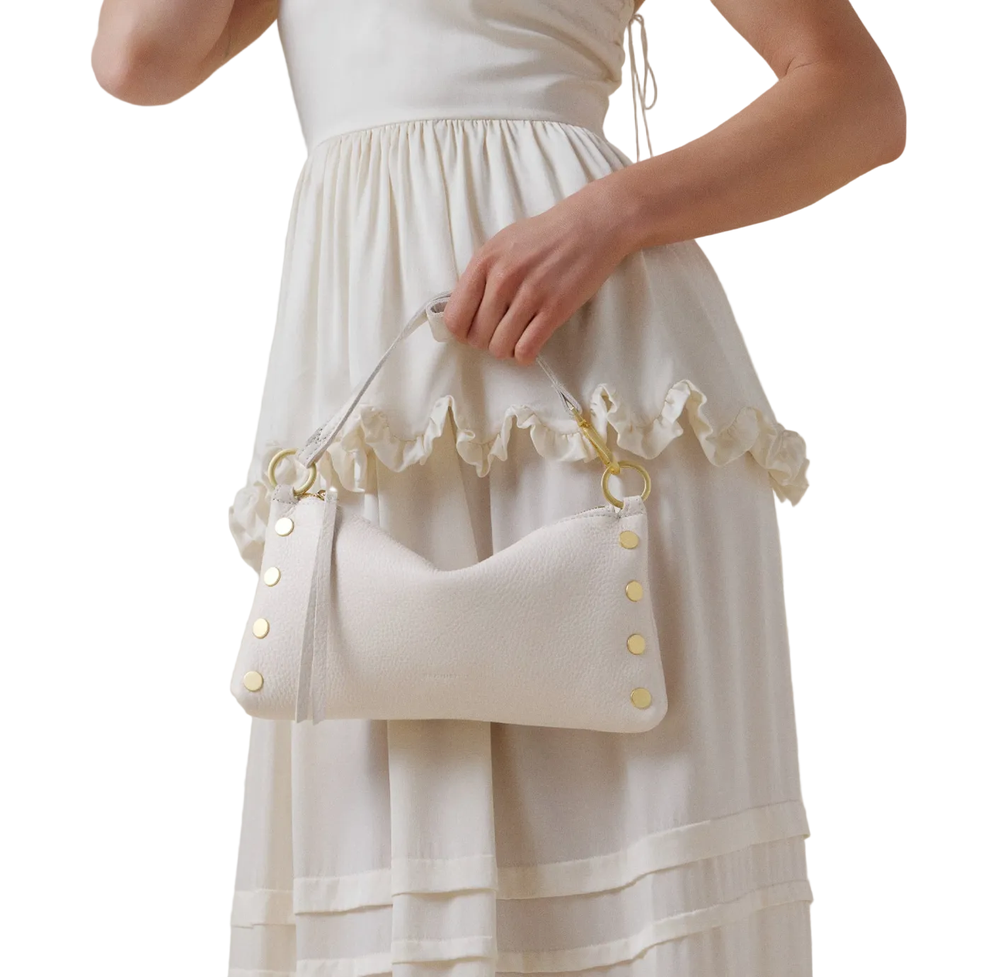 White dress with ruffled details and white purse with gold details held by a person against a plain background