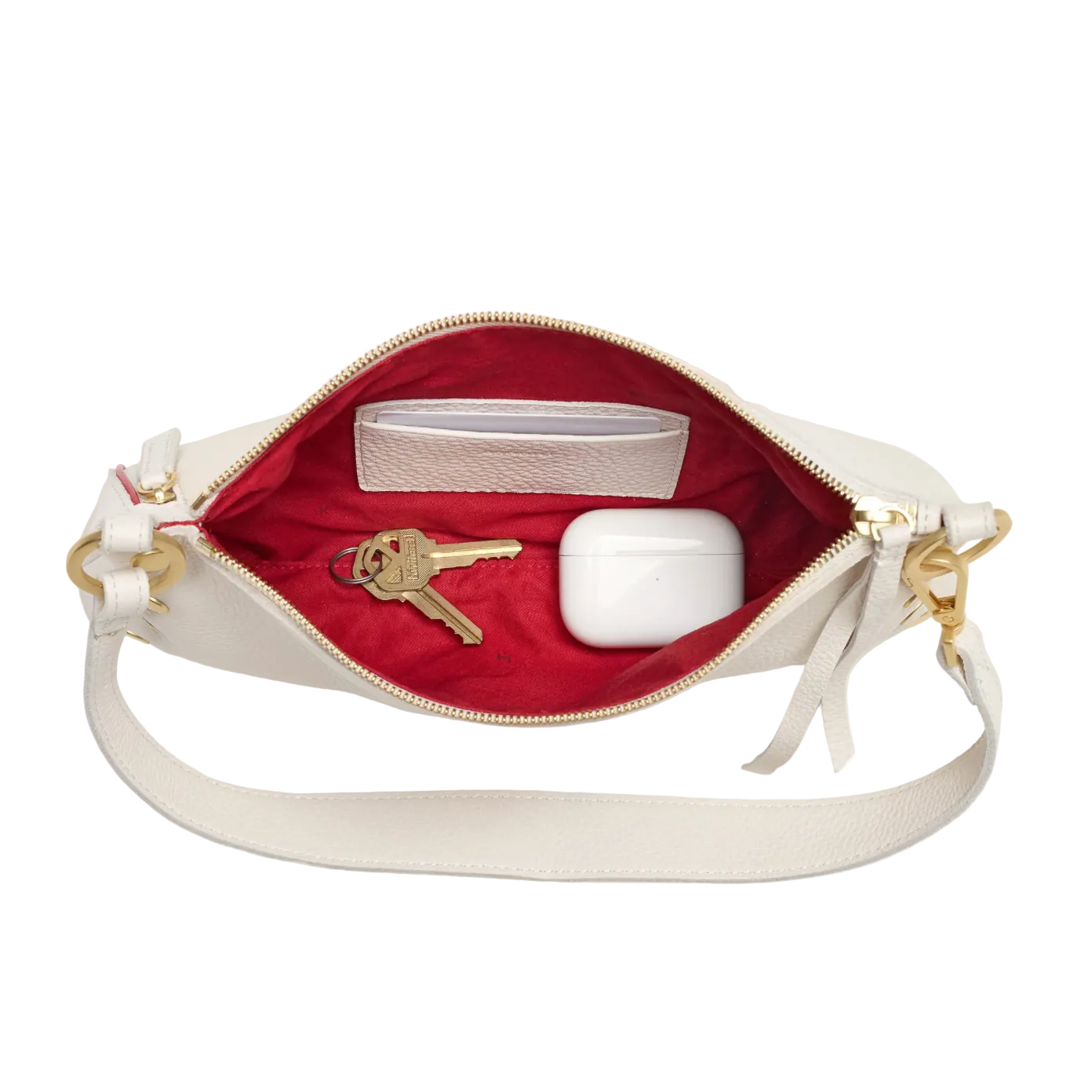 White handbag with gold accents open to reveal a red interior, keys, and a white cup.