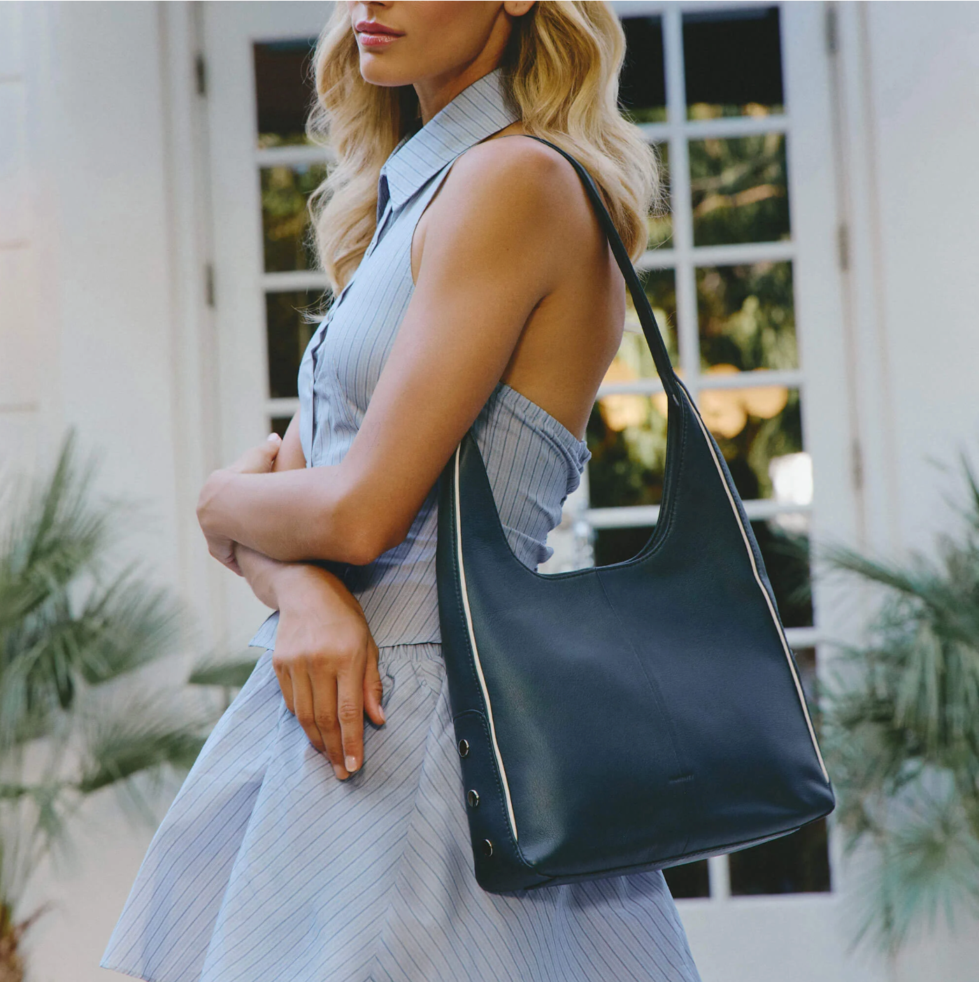 Woman holding a navy blue handbag outdoors