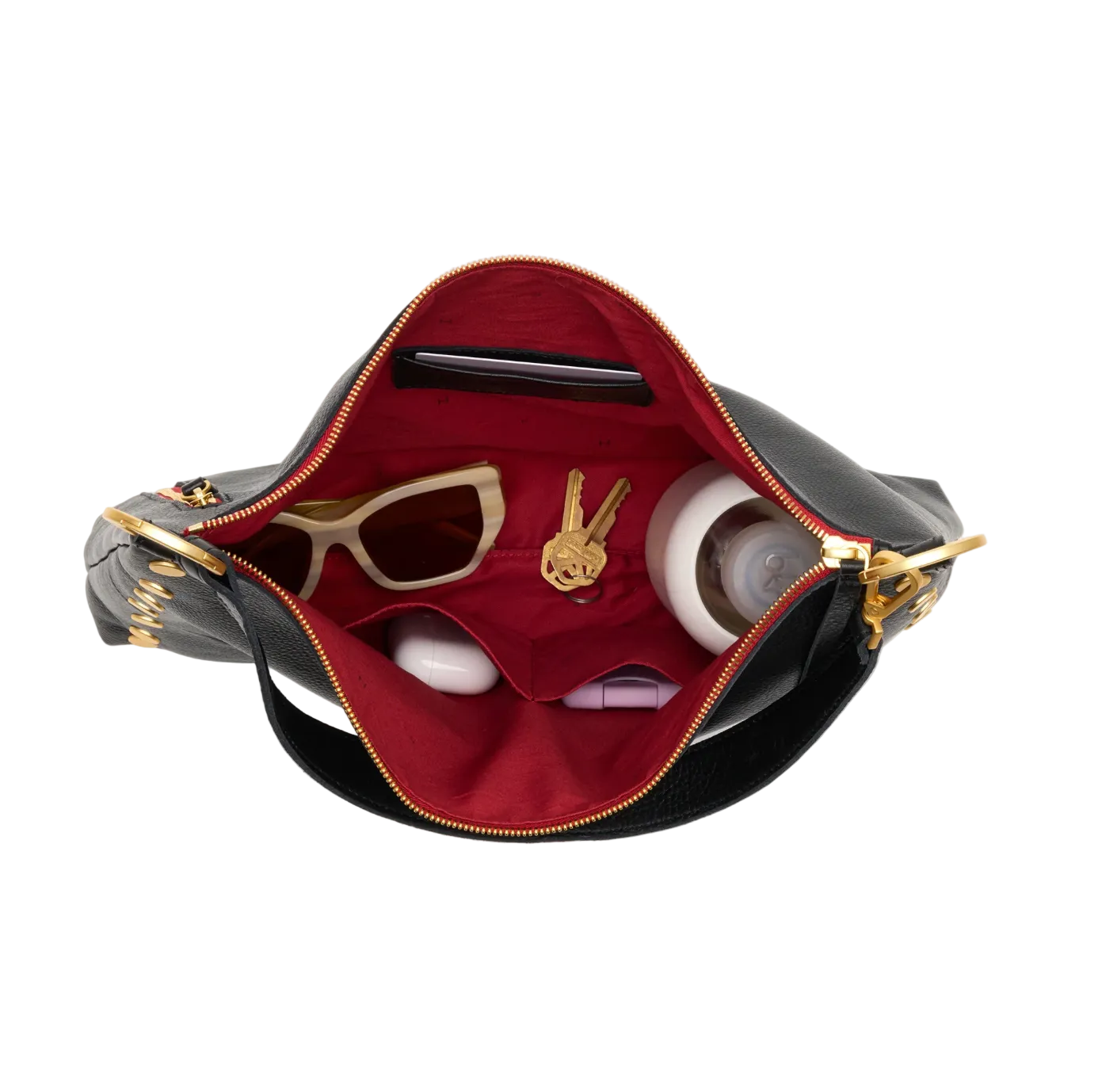 Black handbag with gold accents containing sunglasses and a necklace on a white background