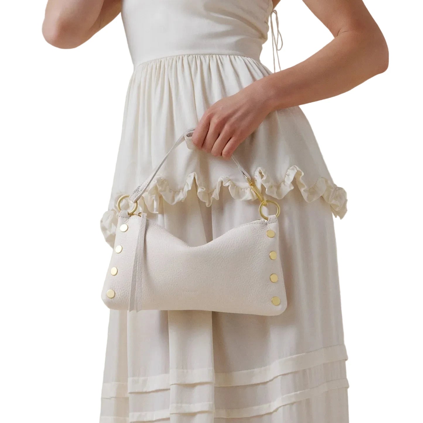 Person wearing a cream-colored dress holding a matching handbag against a plain background