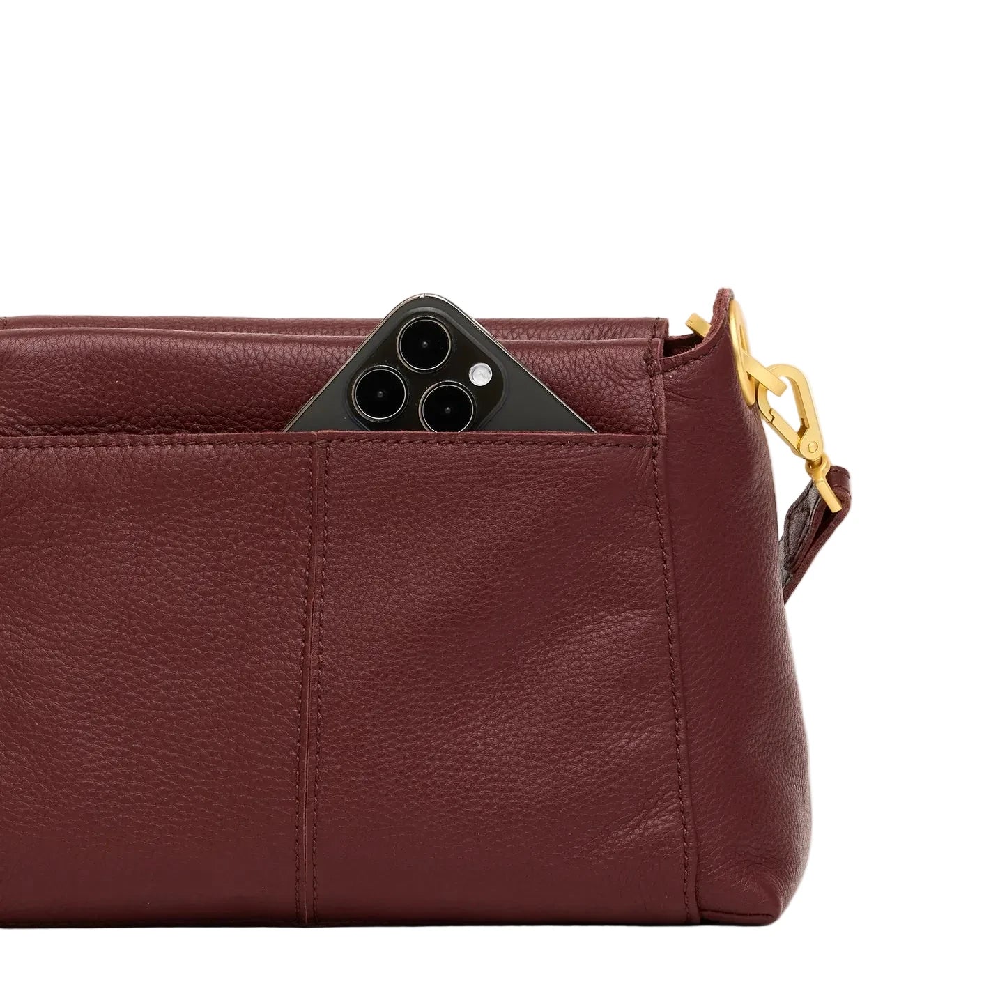 Maroon leather handbag with a phone peeking out of its outer pocket on a white background