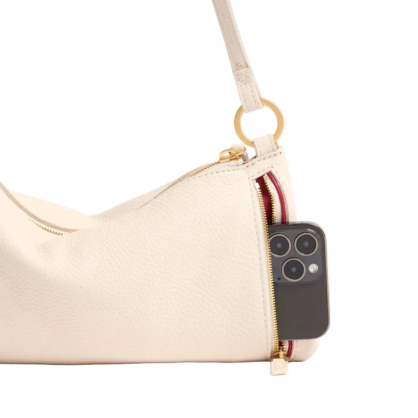 Cream handbag with a cell phone peeking out of a red and gold zippered exterior pocket. 