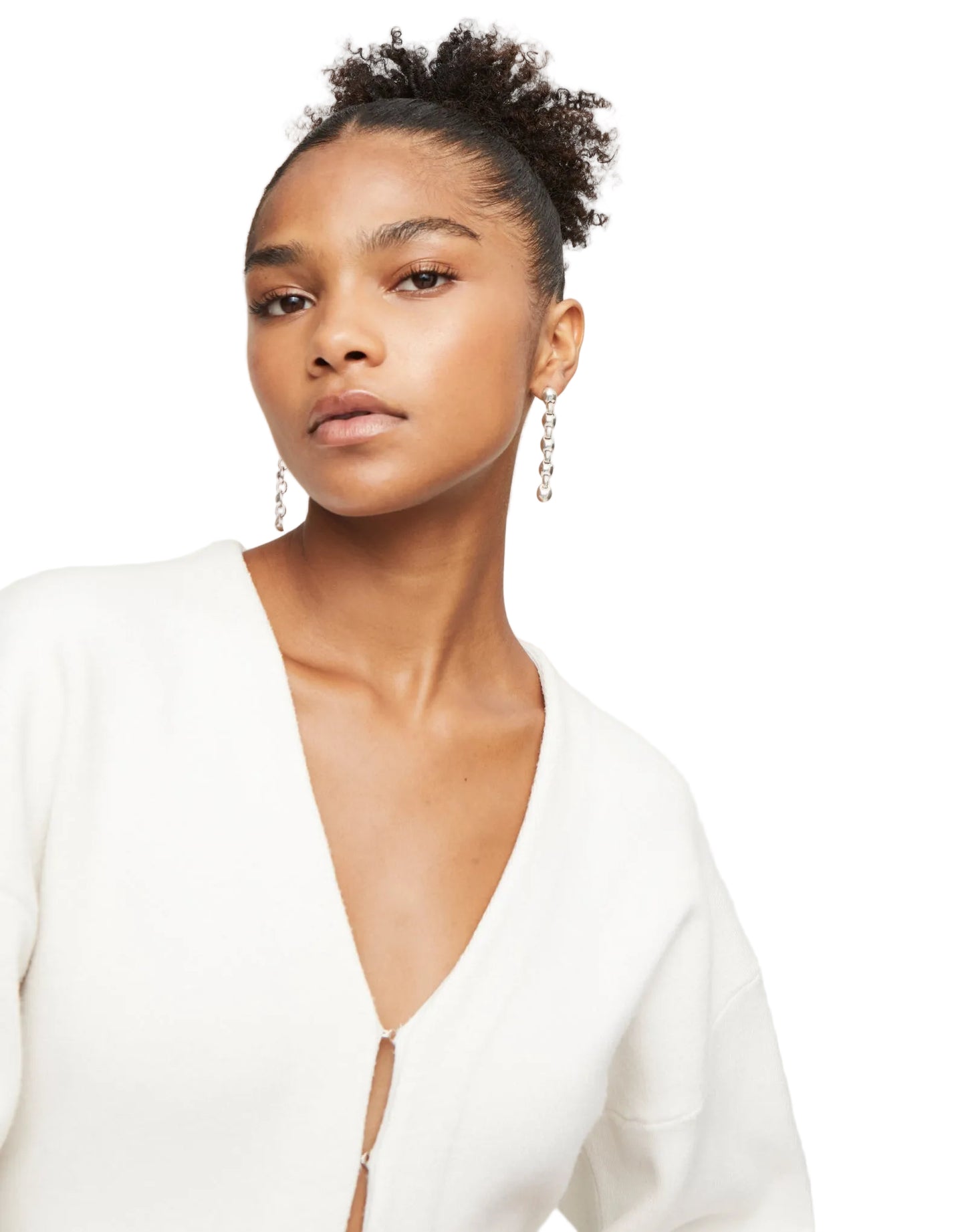 Woman wearing a white top with a deep neckline against a plain background